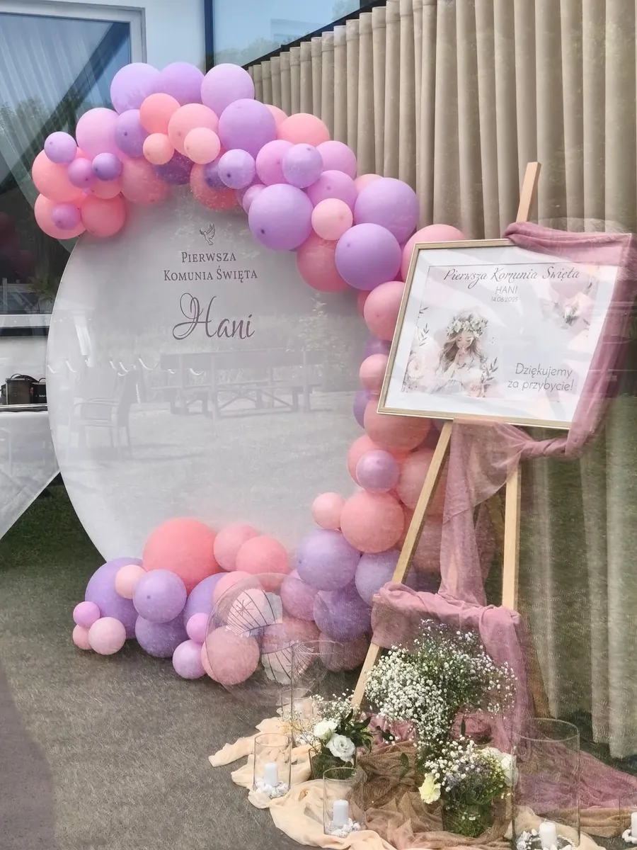 Girlanda balonowa w różach i fioletach wokół tablicy komunijnej